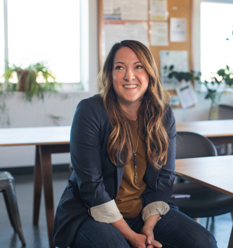 Female instructor smiling and sitting in a classroom
