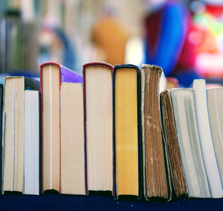 A hand lifting a stack of books