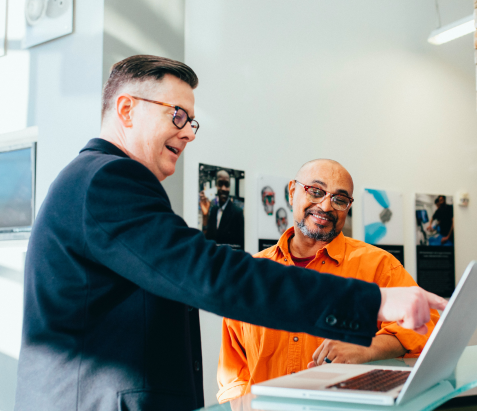 2 man standing up pointing at a screen 