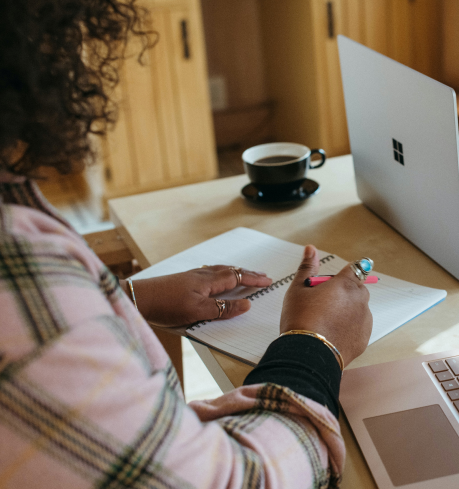 Woman taking notes on a notebook and using her laptop