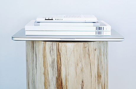 A stack of books and a laptop on a log
