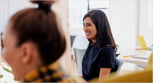 Female educator sitting at a conferance and smiling