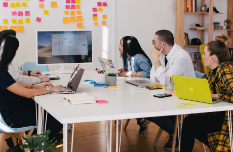 Group of people in a meeting room with laptops and engaging in a virtual conferance