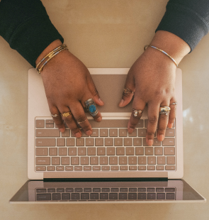 Hands decorated in jewlery and typing on keyboard