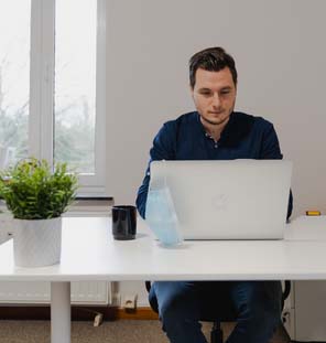 male sitting at desk looking at laptop