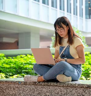woman sitting down outside with laptop on lap