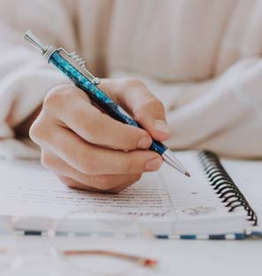 Close up image of handing hold a pen on top of notebook