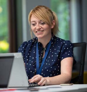 Female educator sitting at a desk with laptop and smiling