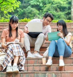 group of friends looking at book and computer on steps