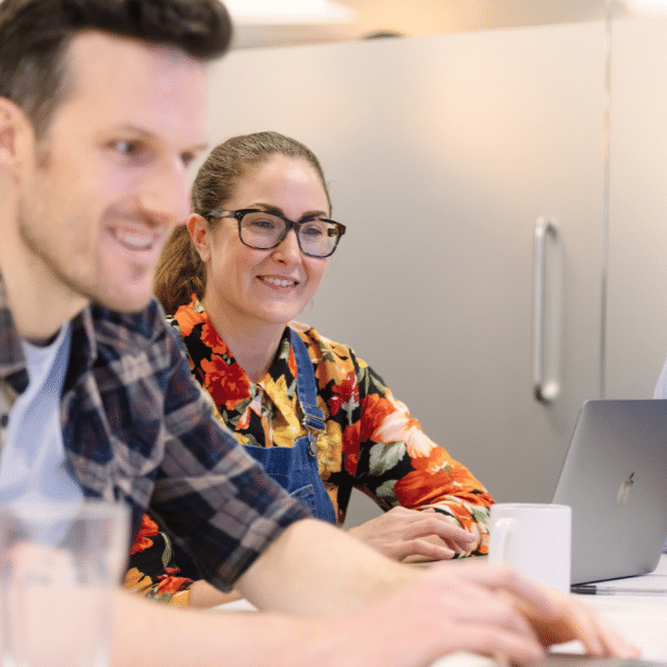 coworkers smiling while looking at a laptop together