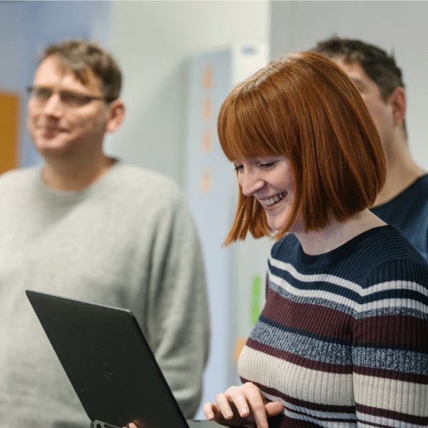 Woman smiling with coworkers holding her laptop