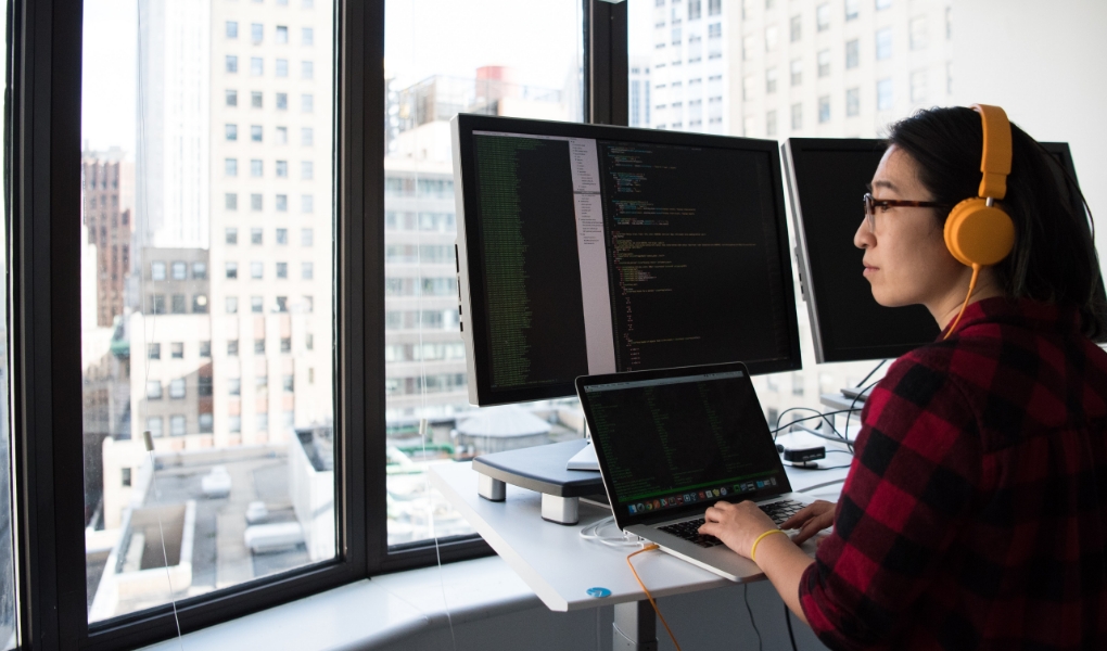 Group of professionals sitting at an office desk looking at a monitor. 