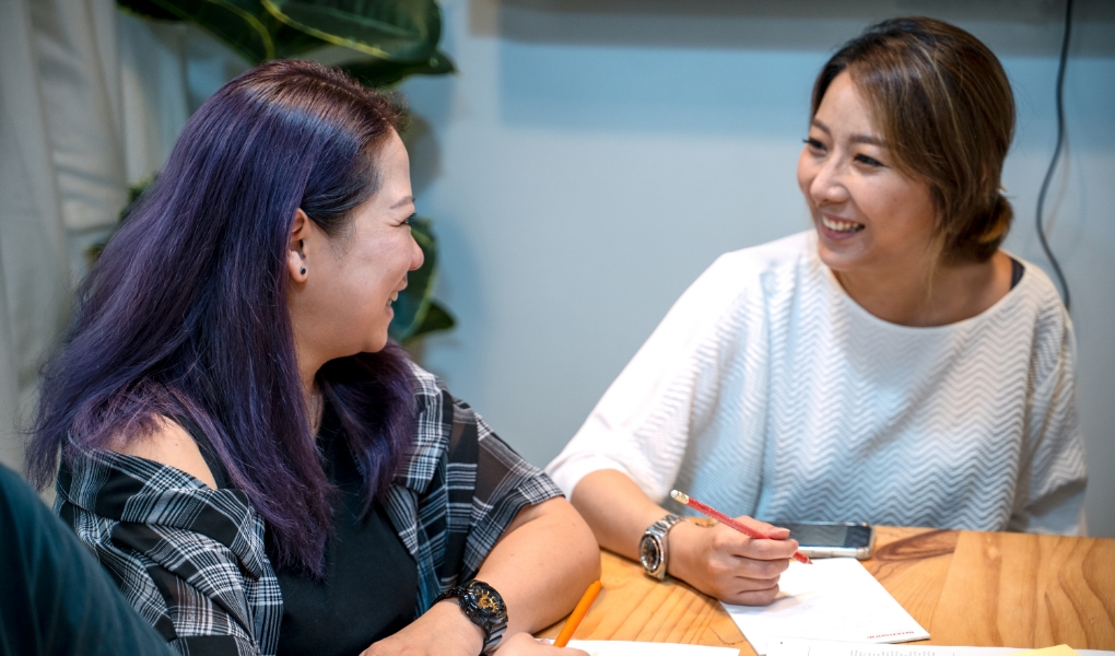 Two professional women smiling at each other. 