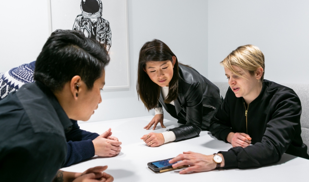 Group of young professionals in a meeting room engaging in a mobile conferance.
