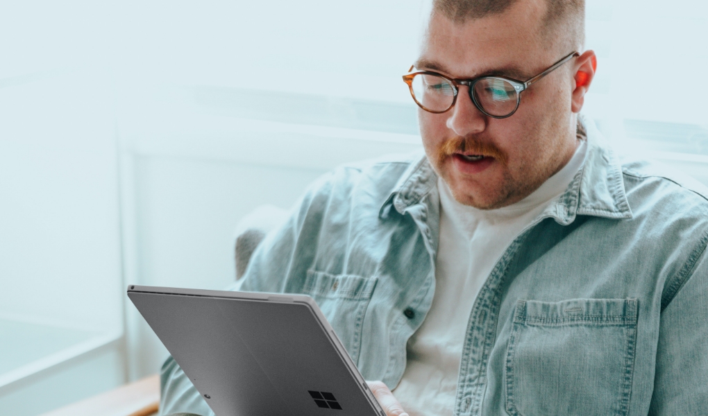 Man wearing glasses is working on his tablet.