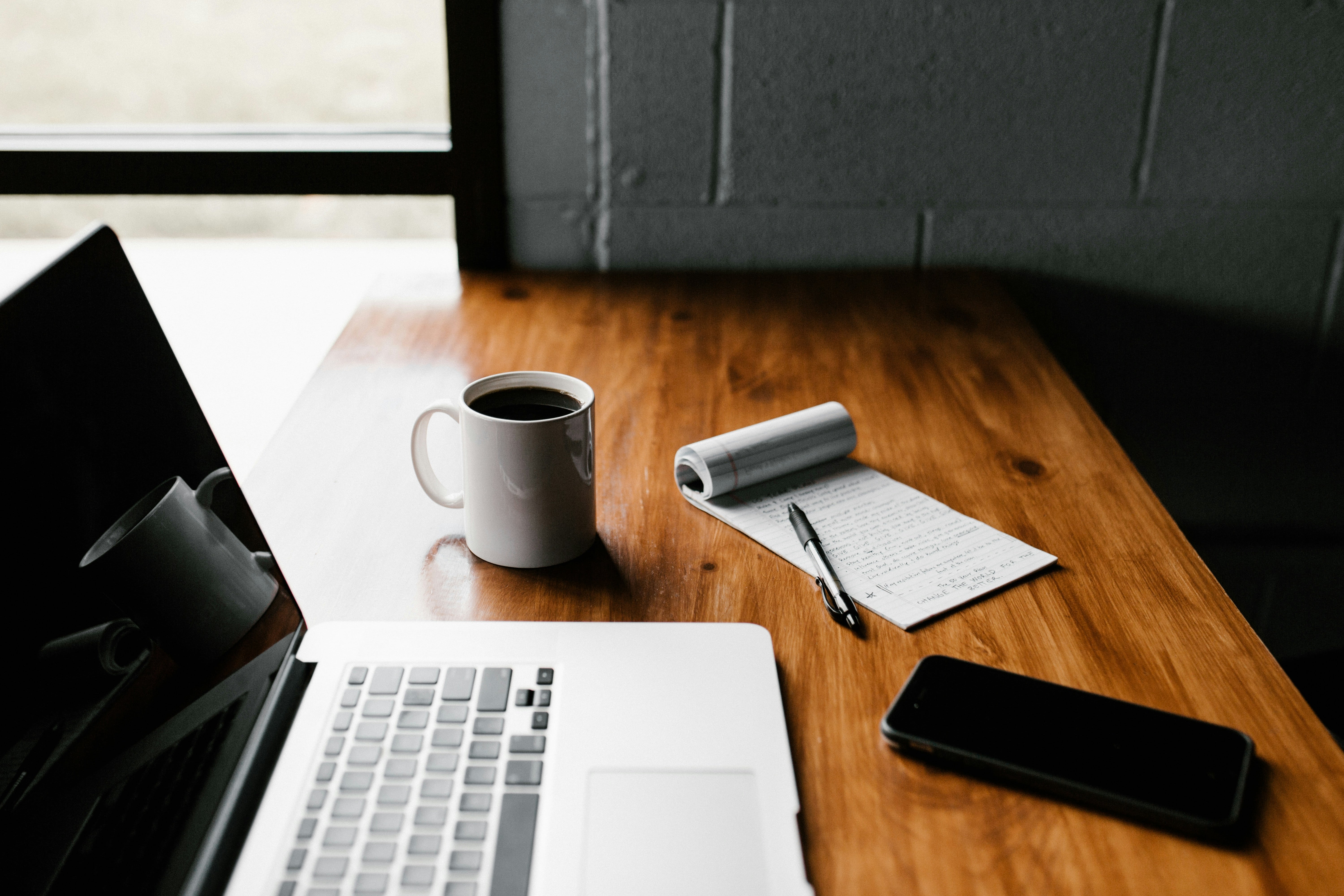 photo of a laptop coffee and notepad sitting on desk
