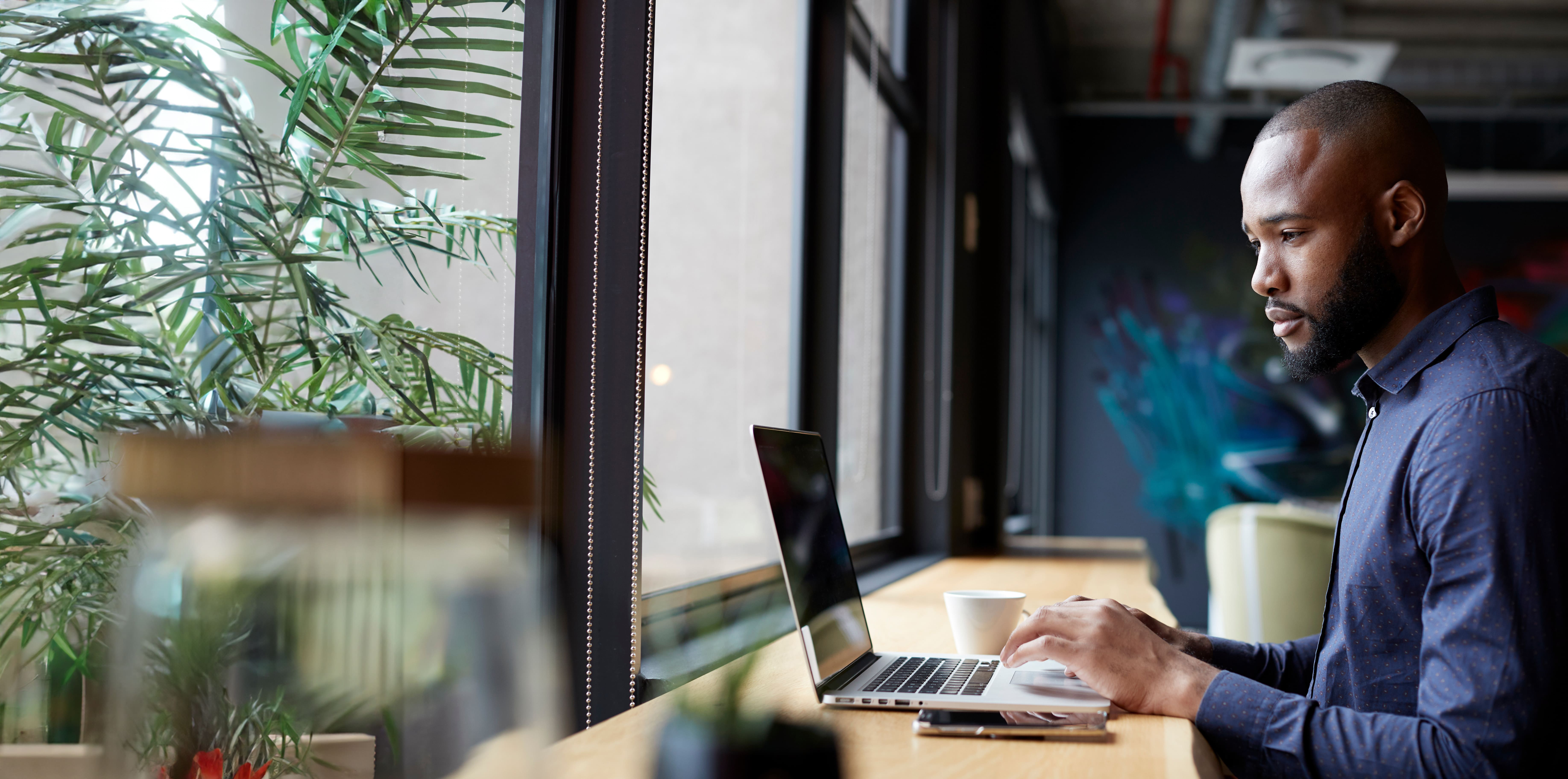 businessman sitting at desk using laptop in front of a window