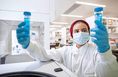 Woman in a lab observing test tubes 