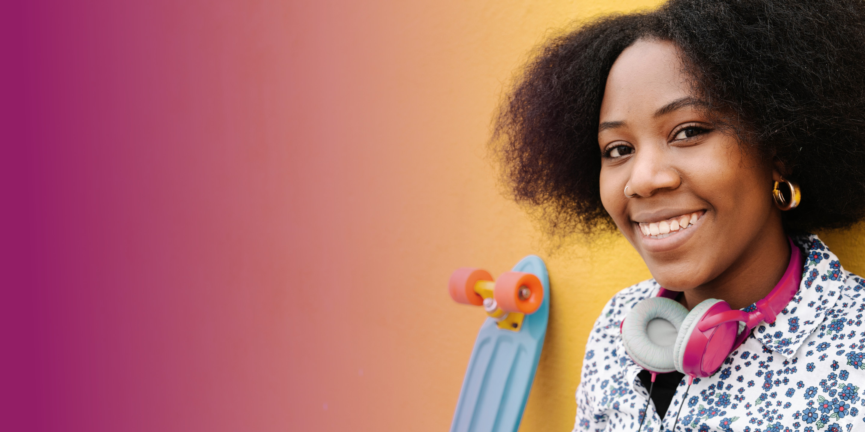Young woman smiling and a skateboard behind her.