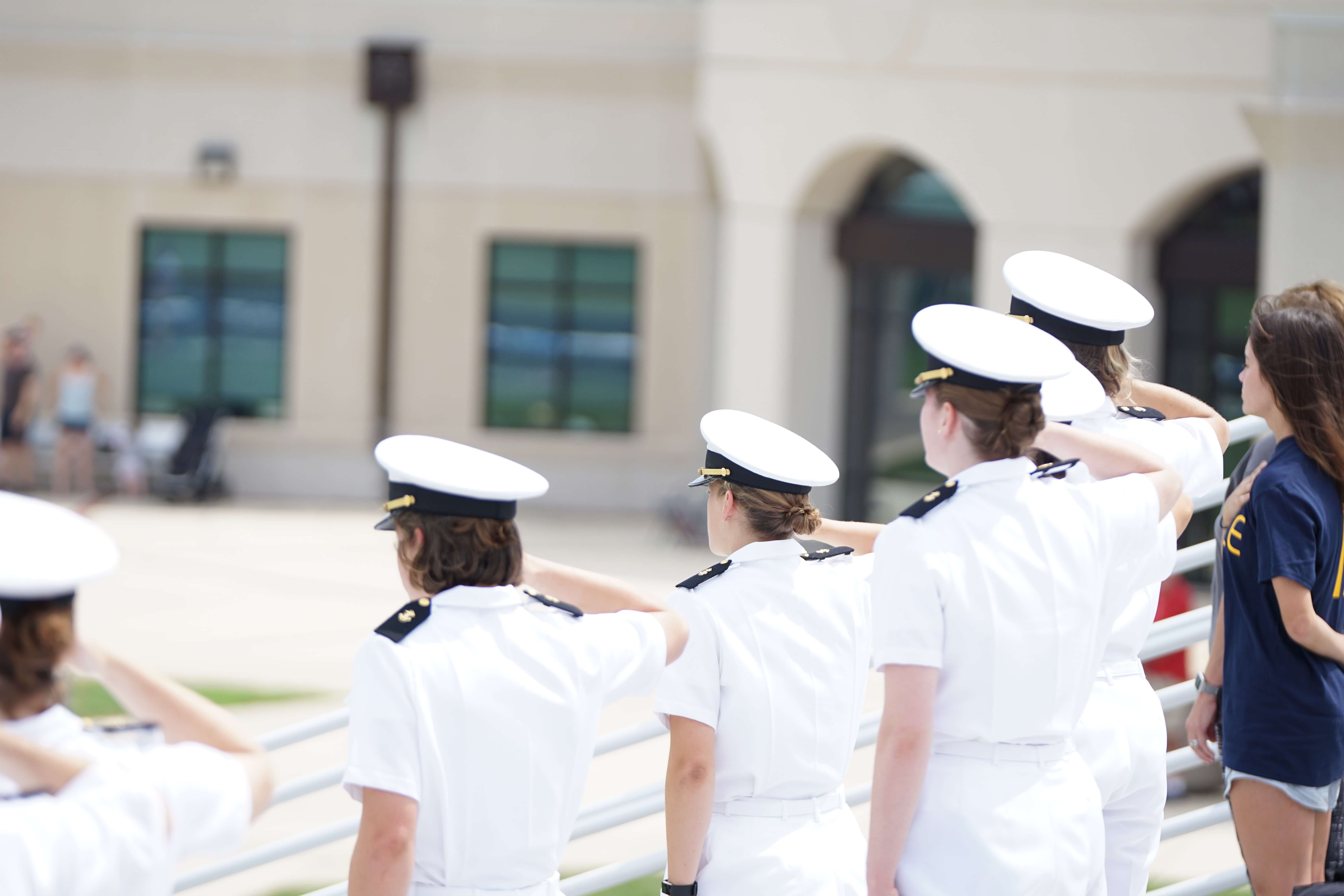 Group of people in white costum standing and saluting.