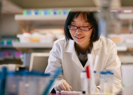 Woman working in a lab. She is wearing glasses and a white lab coat