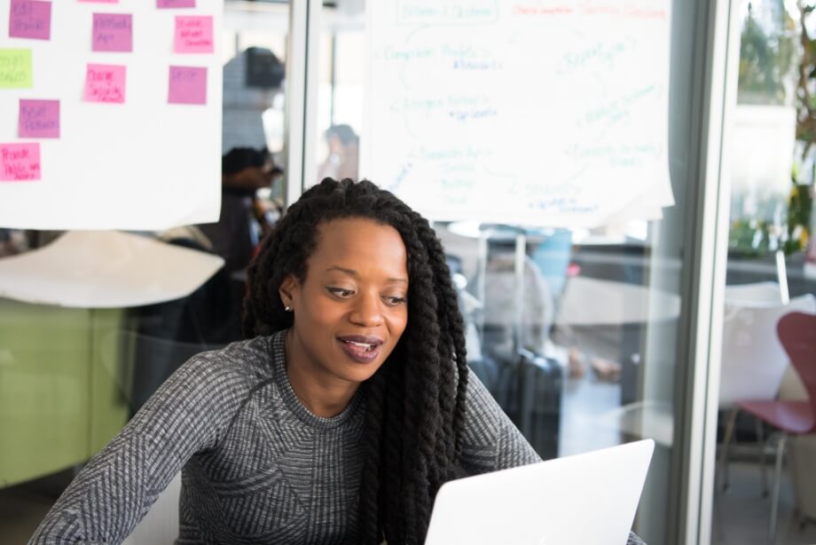 Young woman sitting in a workplace confernace room and looking at her laptop.  