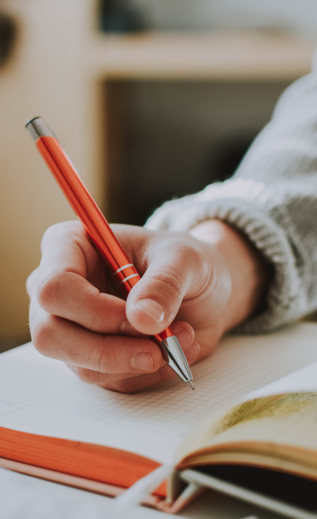 Close up of a hand writing in a journal with a pen