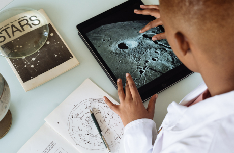 Person wearing a lab coat and looking at tablet screen. 