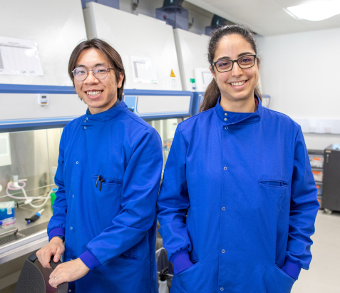 two scientists in uniform smiling 