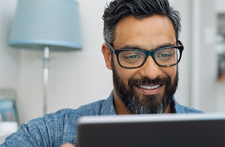 Man with glasses reading on a tablet 