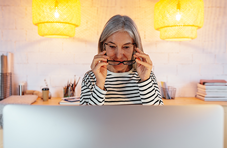 Woman puting glasses on in front of a monitor