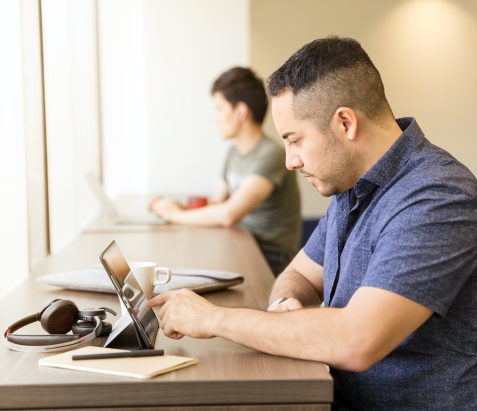 Man sitting at a desk and scrolling through a tablet 