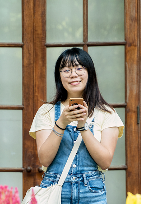 Female student smiling and using her mobile phone