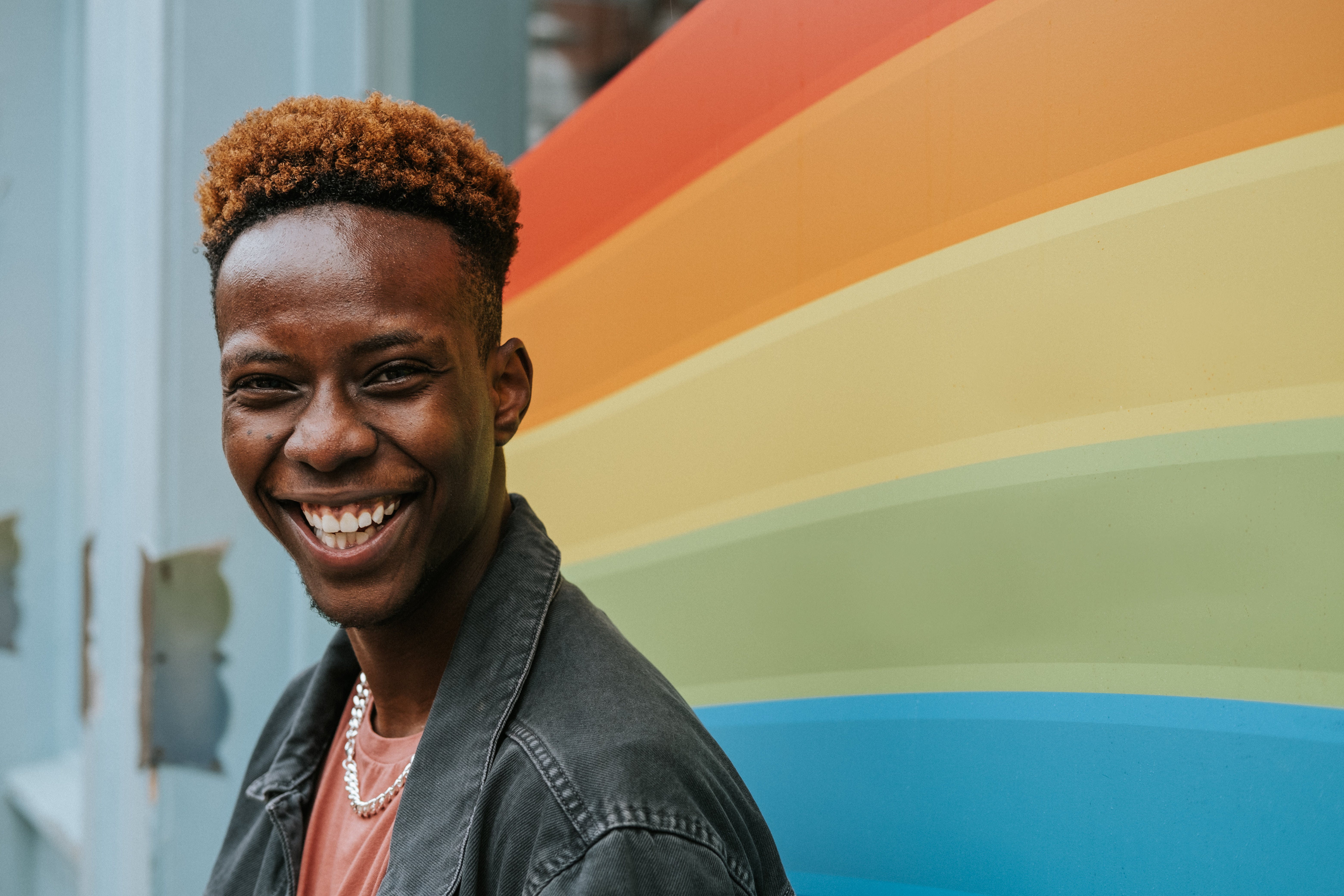 Man smiling in front of rainbow.