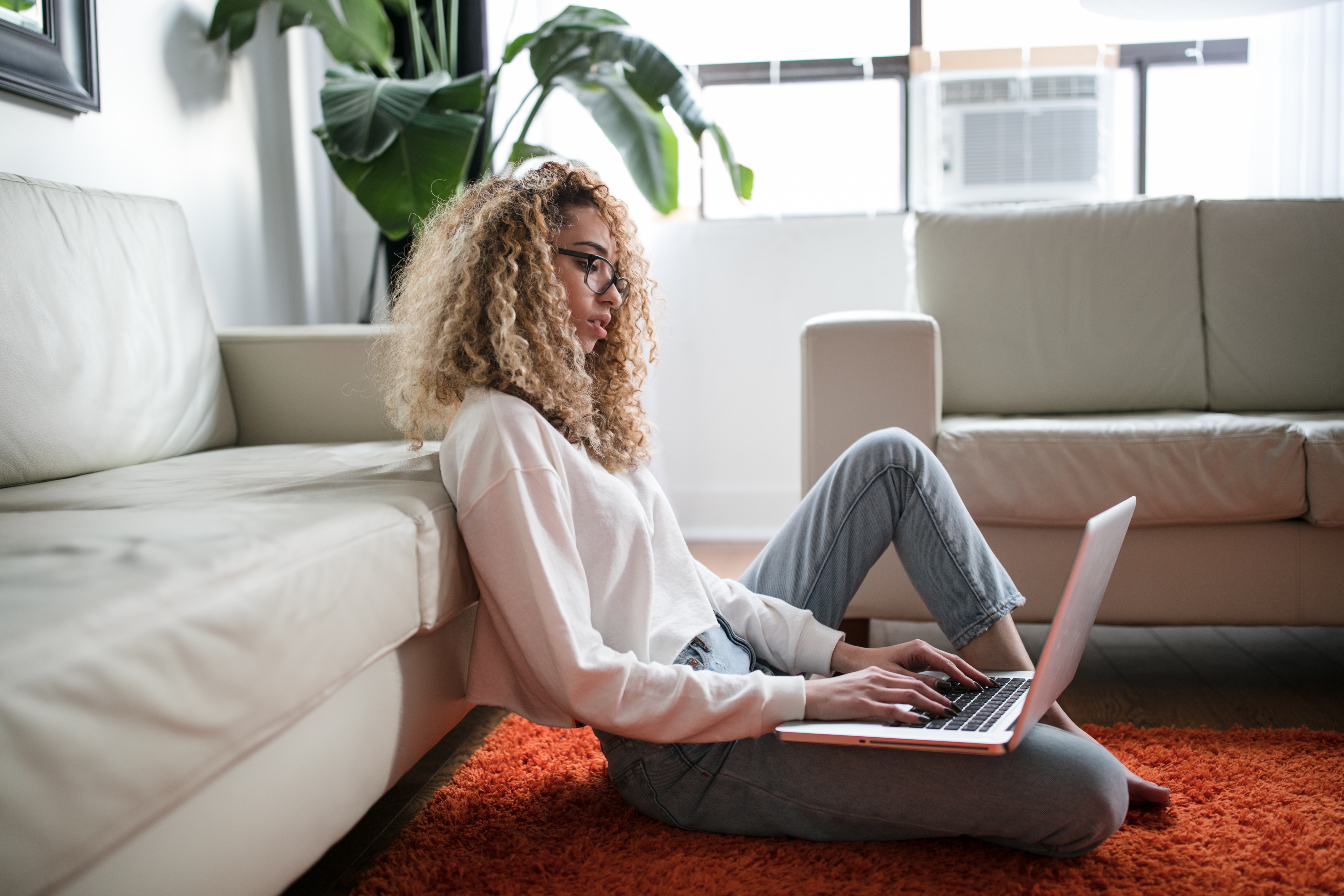 woman sitting on floor and leaning on couch using laptop photo